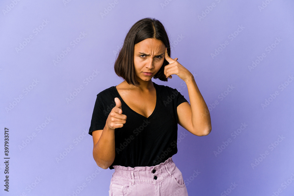 Young mixed race woman pointing temple with finger, thinking, focused on a task. Young mixed race woman pointing temple with finger, thinking, focused on a task.