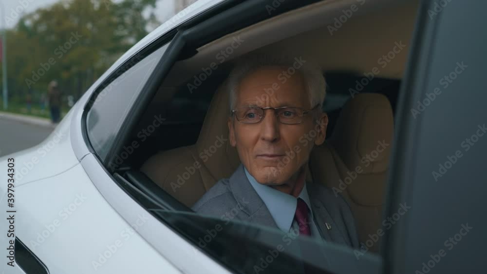 old businessman rides in the back seat of a car old businessman rides in the back seat of a car