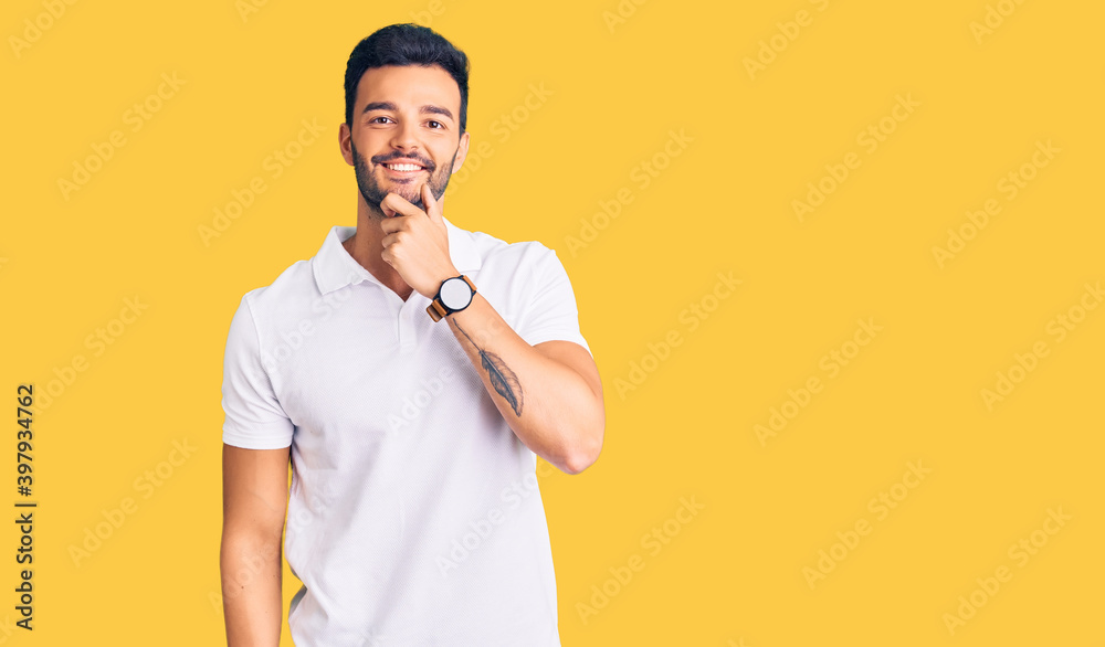 Young handsome hispanic man wearing casual clothes looking confident at the camera smiling with crossed arms and hand raised on chin. thinking positive. Young handsome hispanic man wearing casual clothes looking confident at the camera smiling with crossed arms and hand raised on chin. thinking positive.