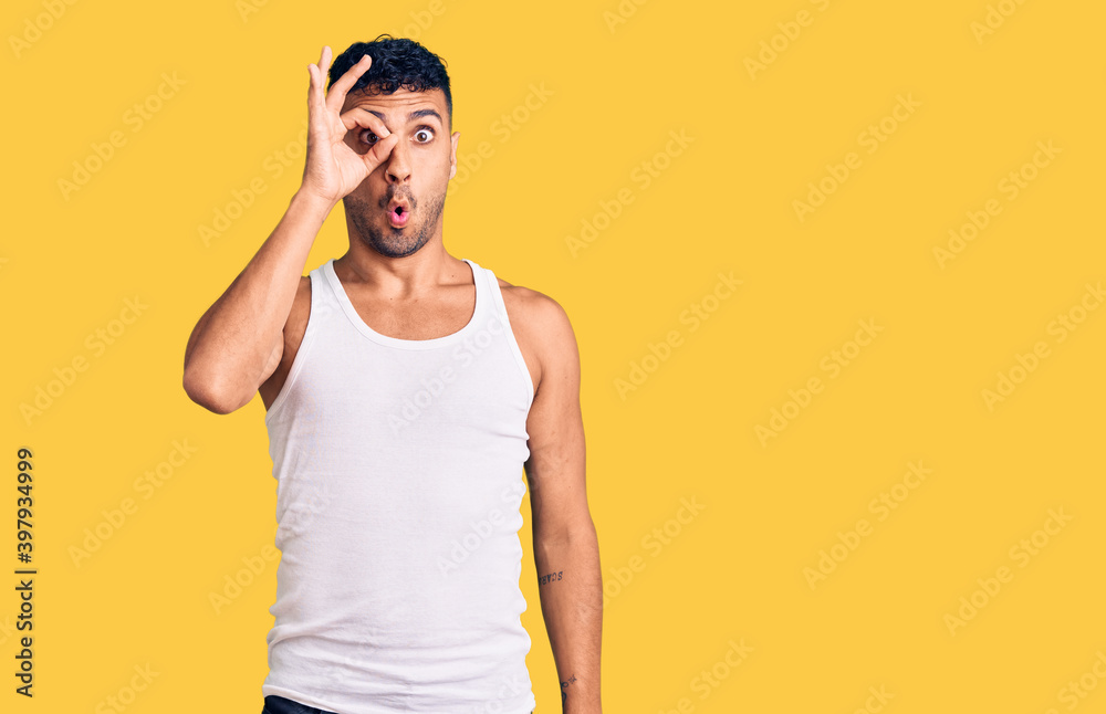 Young hispanic man wearing casual clothes doing ok gesture shocked with surprised face, eye looking through fingers. unbelieving expression. Young hispanic man wearing casual clothes doing ok gesture shocked with surprised face, eye looking through fingers. unbelieving expression.