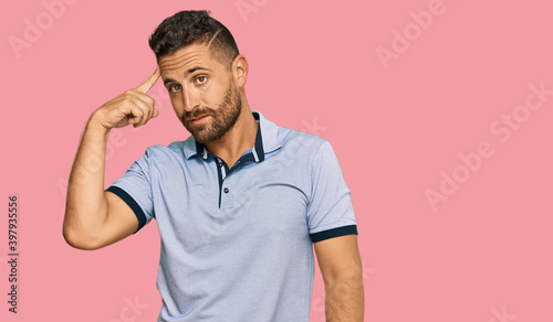 Handsome man with beard wearing casual clothes smiling pointing to head with one finger, great idea or thought, good memory