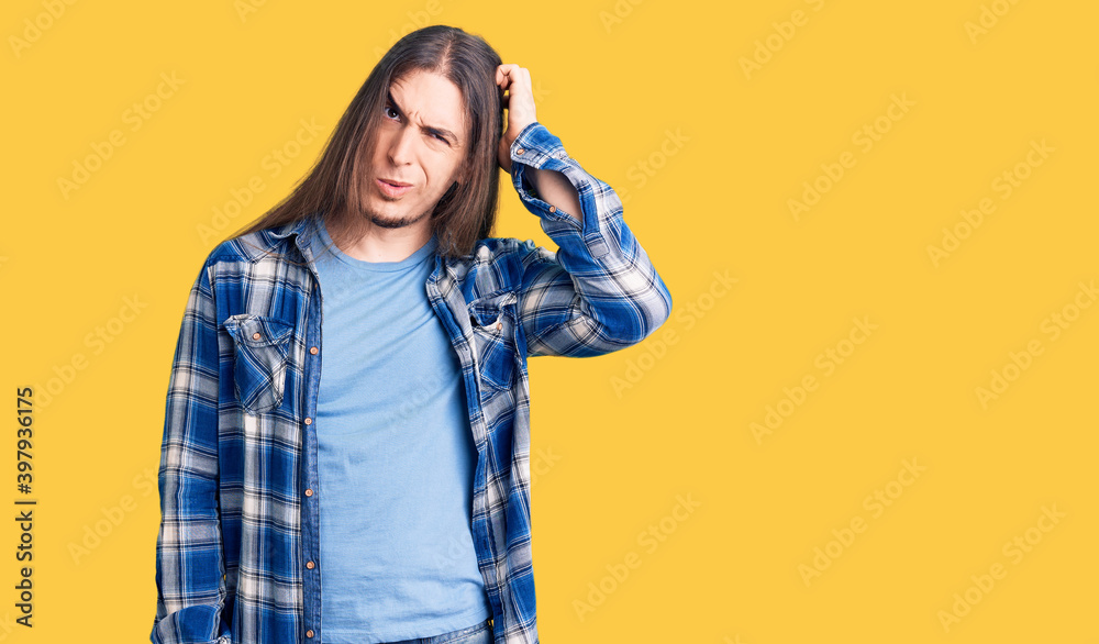Young adult man with long hair wearing casual shirt confuse and wonder about question. uncertain with doubt, thinking with hand on head. pensive concept. Young adult man with long hair wearing casual shirt confuse and wonder about question. uncertain with doubt, thinking with hand on head. pensive concept.