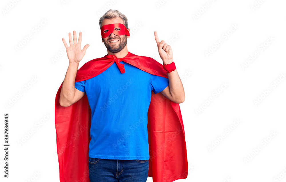 Young blond man wearing super hero custome showing and pointing up with fingers number six while smiling confident and happy.