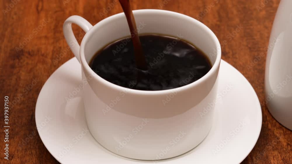 Pouring black coffee into white cup. Close up video, wooden background Pouring black coffee into white cup. Close up video, wooden background