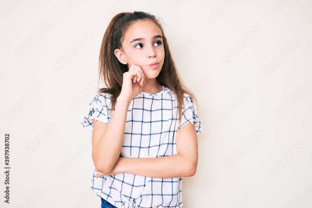 Cute hispanic child girl wearing casual clothes serious face thinking about question with hand on chin, thoughtful about confusing idea Cute hispanic child girl wearing casual clothes serious face thinking about question with hand on chin, thoughtful about confusing idea