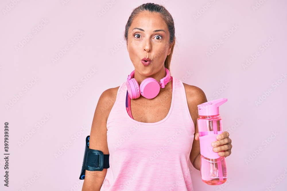 Φωτογραφία Middle age hispanic woman wearing sportswear holding water bottle scared and ama