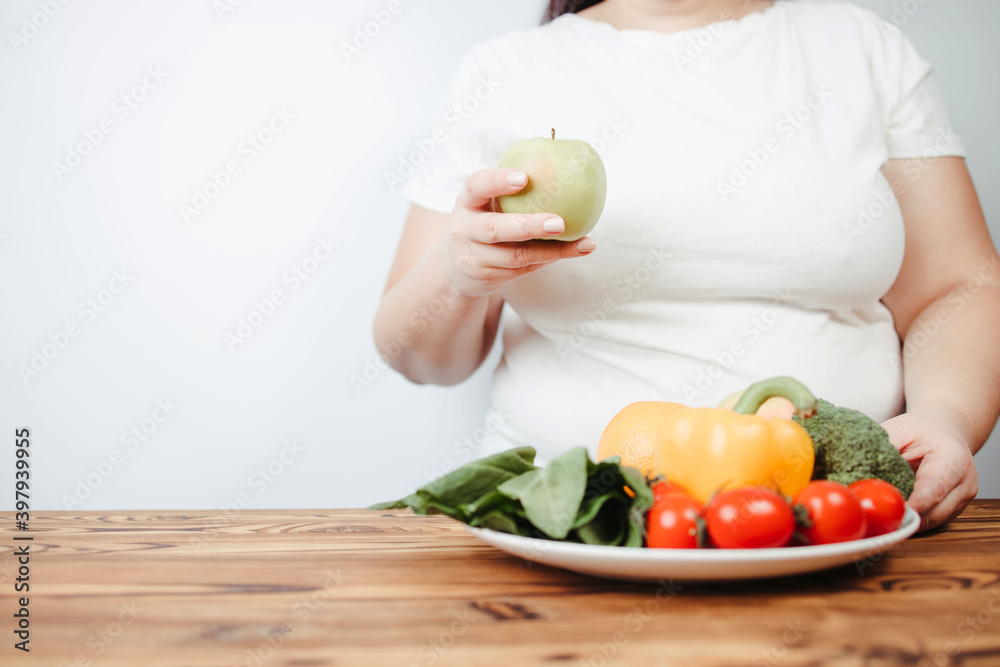 Fat woman snacking with fruits and vegetables Fat woman snacking with fruits and vegetables