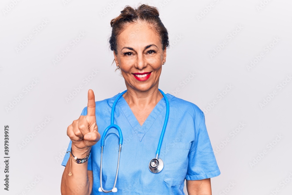 Middle age brunette nurse woman wearing uniform and stethoscope over white background smiling with an idea or question pointing finger up with happy face, number one Middle age brunette nurse woman wearing uniform and stethoscope over white background smiling with an idea or question pointing finger up with happy face, number one