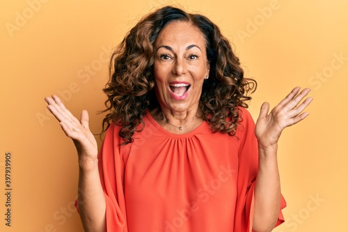 Middle age hispanic woman wearing casual clothes celebrating victory with happy smile and winner expression with raised hands
