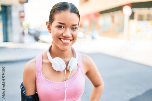 Free Download Young beautiful hispanic sport woman wearing runner outfit and headphones smiling happy at the town - GFXLoad