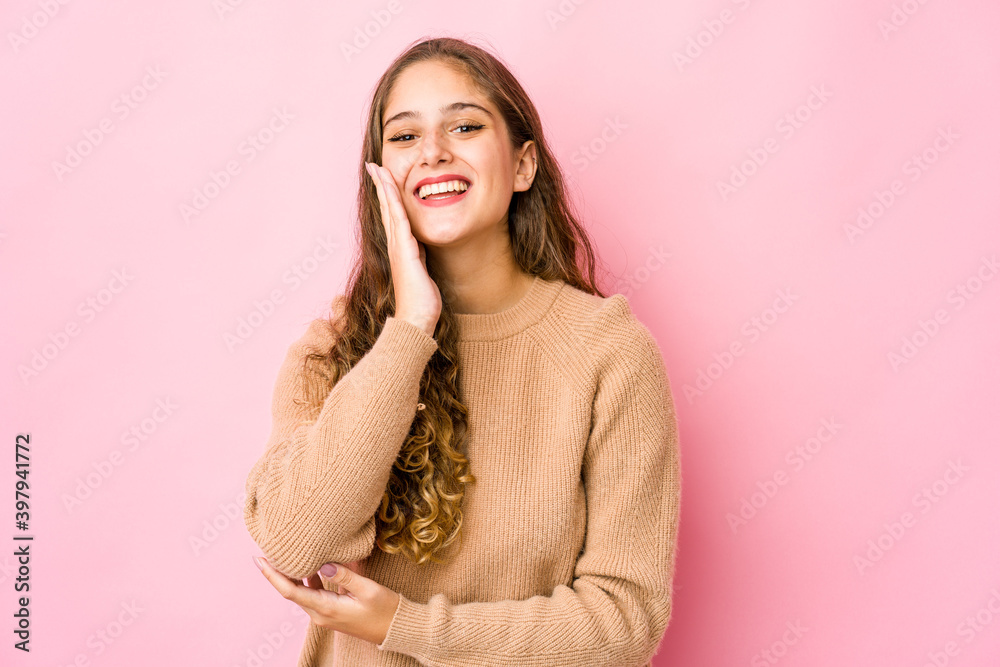 Young caucasian woman laughs happily and has fun keeping hands on stomach.