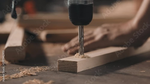 Closeup of unrecognizable strong male hands screwing into piece of wood making diy furniture in carpentry photo