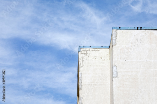 Top of a Concrete Building with Repair Patches against a Cloudy Blue Sky