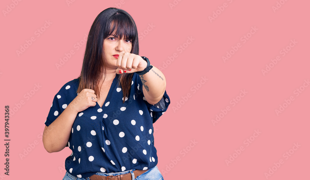 Young plus size woman wearing casual clothes punching fist to fight, aggressive and angry attack, threat and violence Young plus size woman wearing casual clothes punching fist to fight, aggressive and angry attack, threat and violence