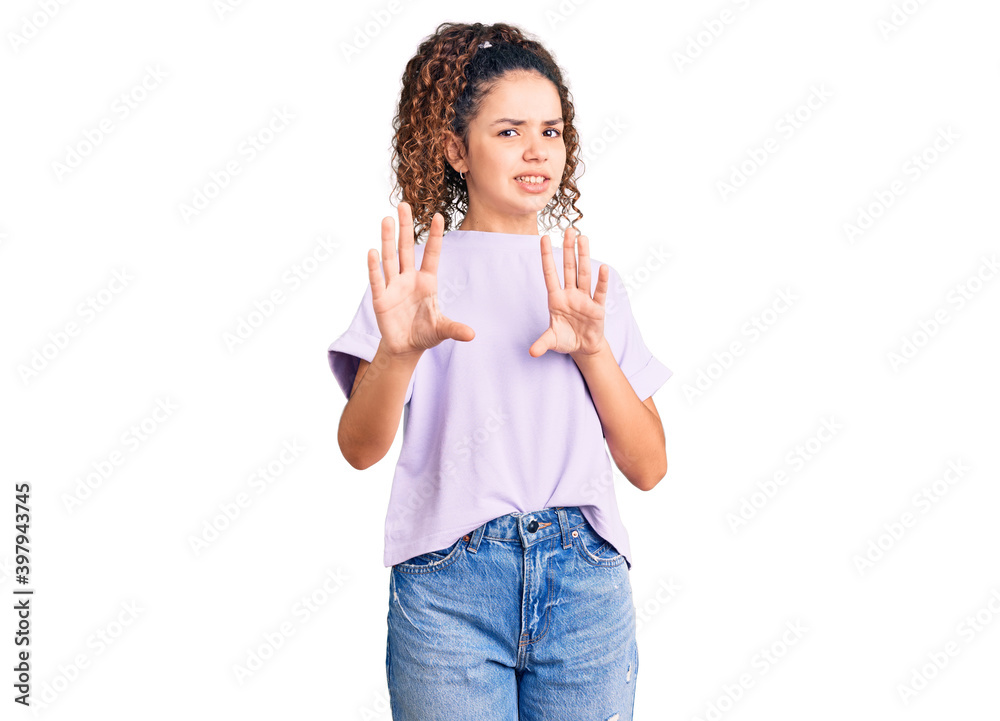 Beautiful kid girl with curly hair wearing casual clothes disgusted expression, displeased and fearful doing disgust face because aversion reaction. with hands raised Beautiful kid girl with curly hair wearing casual clothes disgusted expression, displeased and fearful doing disgust face because aversion reaction. with hands raised