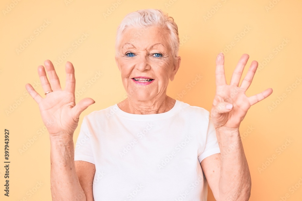 Senior beautiful woman with blue eyes and grey hair wearing classic white tshirt over yellow background showing and pointing up with fingers number nine while smiling confident and happy. Senior beautiful woman with blue eyes and grey hair wearing classic white tshirt over yellow background showing and pointing up with fingers number nine while smiling confident and happy.
