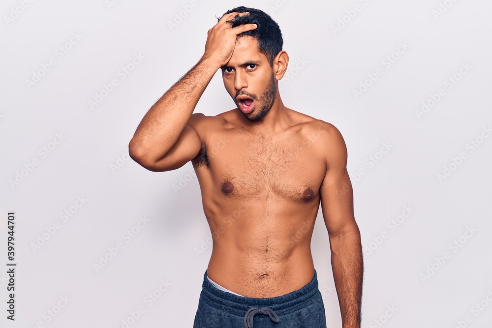 Fototapeta premium Young latin man standing shirtless surprised with hand on head for mistake, remember error. forgot, bad memory concept.