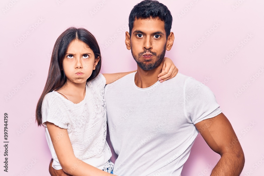 Young father and daughter wearing casual clothes puffing cheeks with funny face. mouth inflated with air, crazy expression. Young father and daughter wearing casual clothes puffing cheeks with funny face. mouth inflated with air, crazy expression.