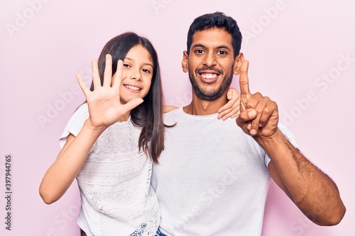 Young father and daughter wearing casual clothes showing and pointing up with fingers number six while smiling confident and happy.