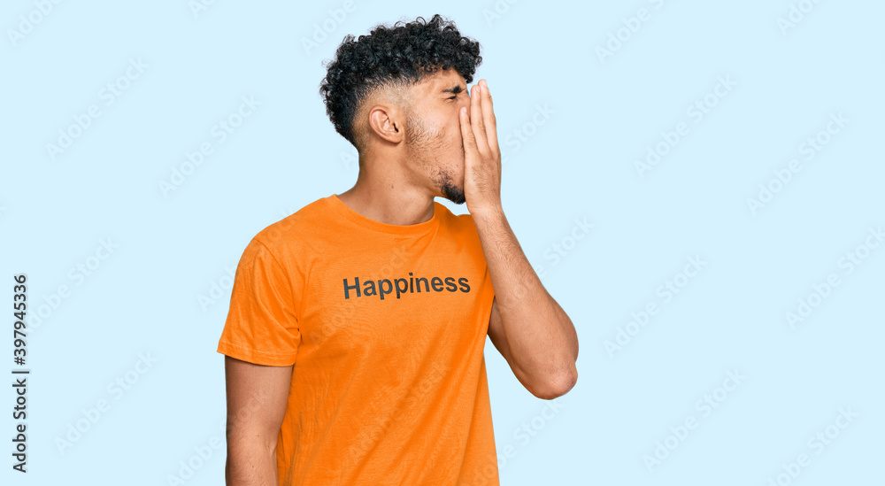 Young arab man wearing tshirt with happiness word message bored yawning tired covering mouth with hand. restless and sleepiness. Young arab man wearing tshirt with happiness word message bored yawning tired covering mouth with hand. restless and sleepiness.