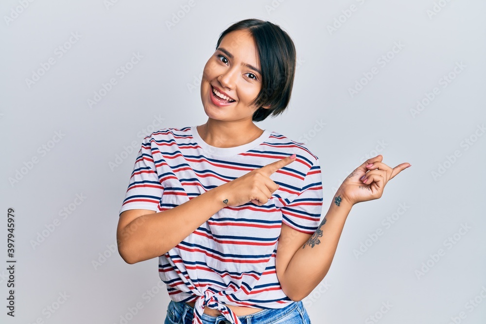 Beautiful young woman with short hair wearing casual clothes smiling and looking at the camera pointing with two hands and fingers to the side. Beautiful young woman with short hair wearing casual clothes smiling and looking at the camera pointing with two hands and fingers to the side.
