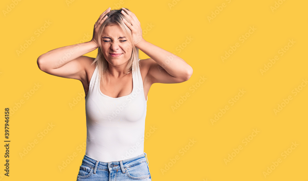 Young beautiful blonde woman wearing casual sleeveless t-shirt suffering from headache desperate and stressed because pain and migraine. hands on head. Young beautiful blonde woman wearing casual sleeveless t-shirt suffering from headache desperate and stressed because pain and migraine. hands on head.