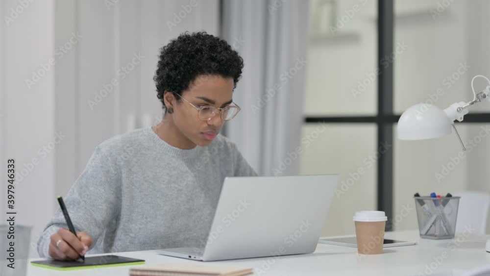 African Woman Designing on Tablet while using Laptop African Woman Designing on Tablet while using Laptop