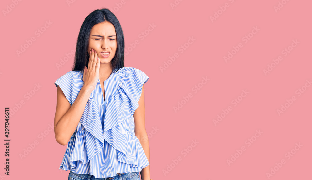 Young beautiful latin girl wearing casual clothes touching mouth with hand with painful expression because of toothache or dental illness on teeth. dentist Young beautiful latin girl wearing casual clothes touching mouth with hand with painful expression because of toothache or dental illness on teeth. dentist