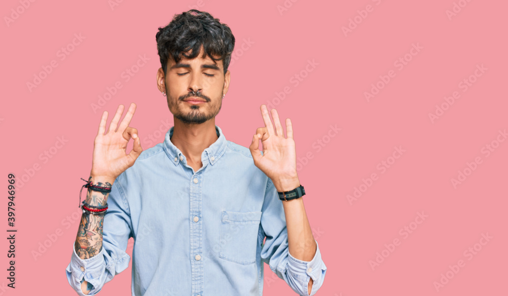 Young hispanic man wearing casual clothes relaxed and smiling with eyes closed doing meditation gesture with fingers. yoga concept. Young hispanic man wearing casual clothes relaxed and smiling with eyes closed doing meditation gesture with fingers. yoga concept.