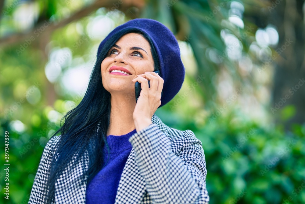 Young beautiful woman wearing french style talking on the smartphone at the park. Young beautiful woman wearing french style talking on the smartphone at the park.