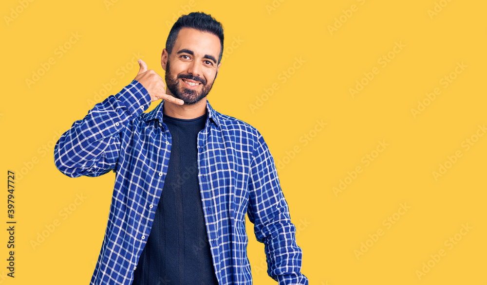Young hispanic man wearing casual clothes smiling doing phone gesture with hand and fingers like talking on the telephone. communicating concepts.