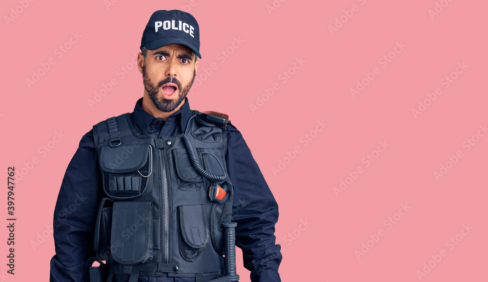 Young hispanic man wearing police uniform in shock face, looking skeptical and sarcastic, surprised with open mouth Young hispanic man wearing police uniform in shock face, looking skeptical and sarcastic, surprised with open mouth