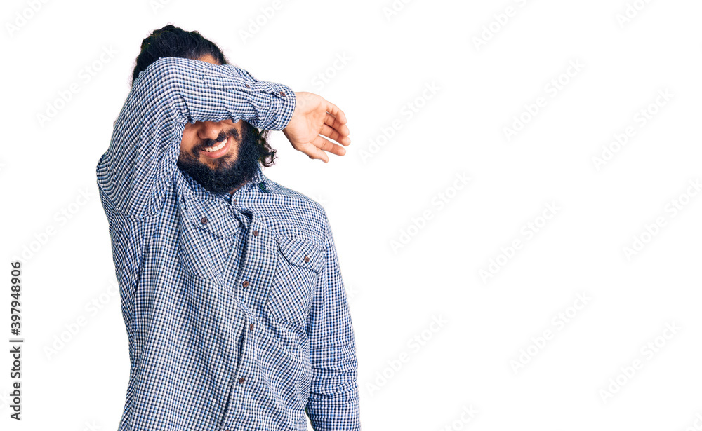 Young arab man wearing casual clothes covering eyes with arm smiling cheerful and funny. blind concept.