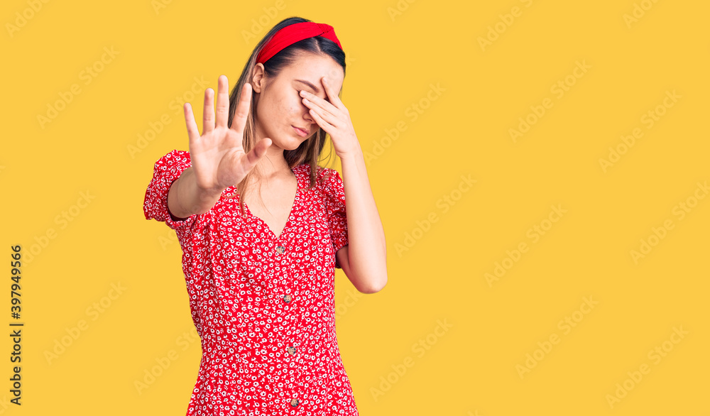 Young beautiful girl wearing dress and diadem covering eyes with hands and doing stop gesture with sad and fear expression. embarrassed and negative concept. Young beautiful girl wearing dress and diadem covering eyes with hands and doing stop gesture with sad and fear expression. embarrassed and negative concept.
