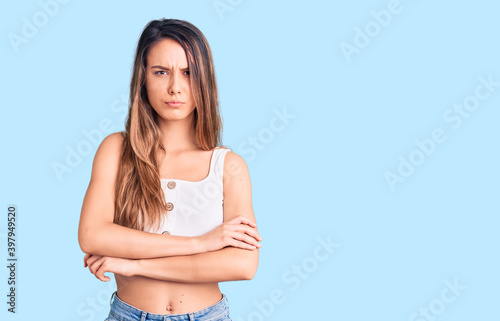 Young beautiful girl wearing casual sleeveless t shirt skeptic and nervous, disapproving expression on face with crossed arms. negative person.