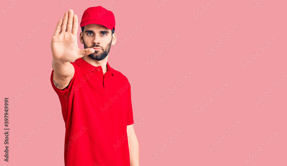 Young handsome man with beard wearing delivery uniform doing stop sing with palm of the hand. warning expression with negative and serious gesture on the face. Young handsome man with beard wearing delivery uniform doing stop sing with palm of the hand. warning expression with negative and serious gesture on the face.