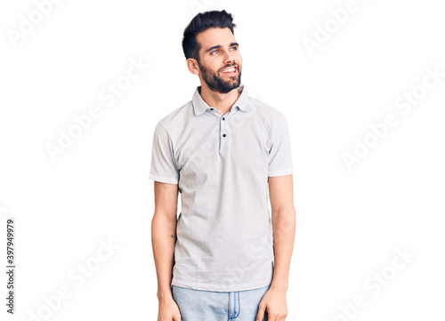 Young handsome man with beard wearing casual polo looking away to side with smile on face, natural expression. laughing confident. © Krakenimages.com