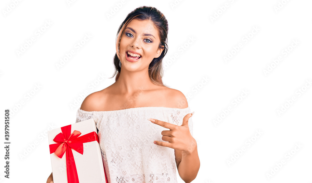 Young beautiful woman holding gift smiling happy pointing with hand and finger