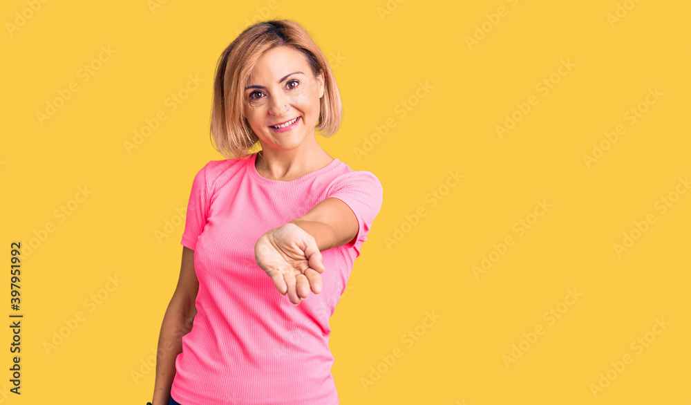 Young blonde woman wearing sportswear smiling cheerful offering palm hand giving assistance and acceptance.
