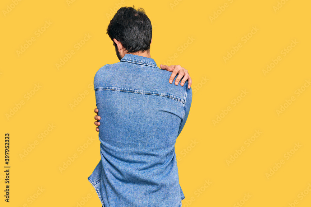 Young hispanic man wearing casual clothes hugging oneself happy and positive from backwards. self love and self care Young hispanic man wearing casual clothes hugging oneself happy and positive from backwards. self love and self care