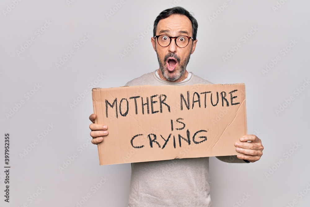 Middle age man asking for environment holding banner with mother nature is crying message scared and amazed with open mouth for surprise, disbelief face Middle age man asking for environment holding banner with mother nature is crying message scared and amazed with open mouth for surprise, disbelief face