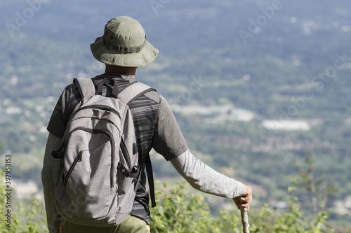 rear back view of one adult man contemplating the view of nature while taking a walk in a tropical landscape view