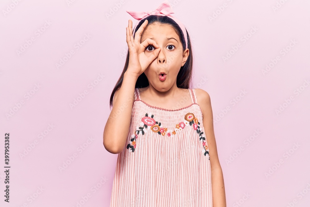 Beautiful child girl wearing casual clothes doing ok gesture shocked with surprised face, eye looking through fingers. unbelieving expression.