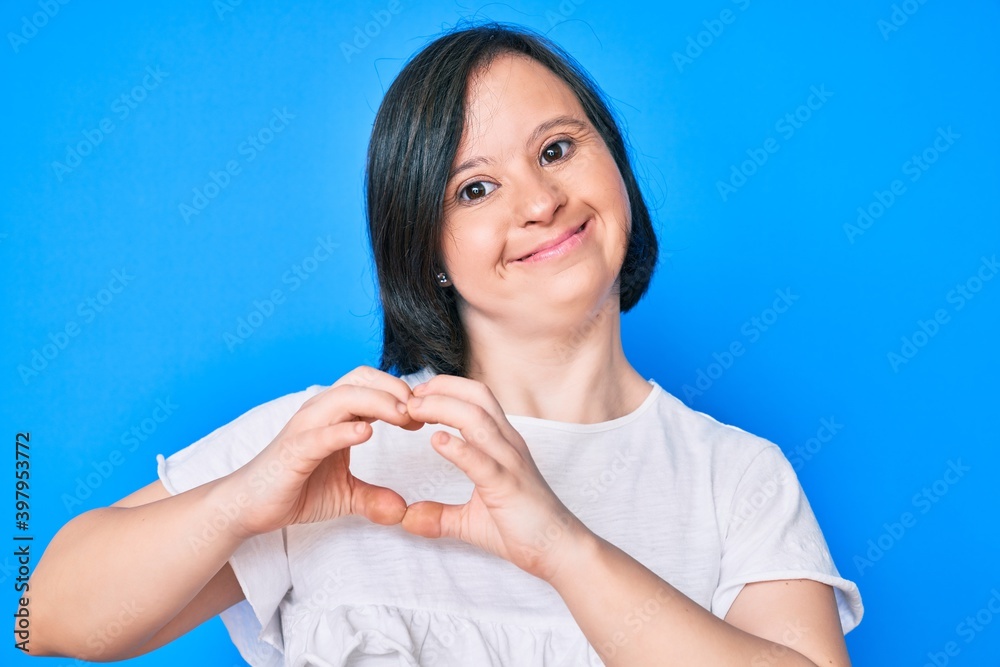 Brunette woman with down syndrome wearing casual clothes smiling in love doing heart symbol shape with hands. romantic concept. Brunette woman with down syndrome wearing casual clothes smiling in love doing heart symbol shape with hands. romantic concept.