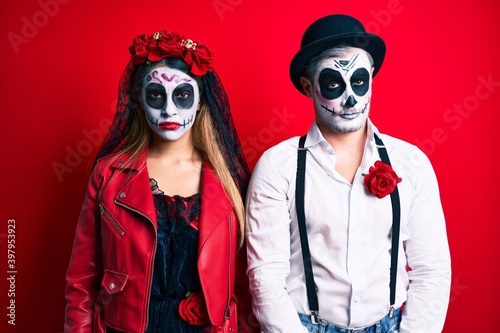 Couple wearing day of the dead costume over red skeptic and nervous, frowning upset because of problem. negative person.