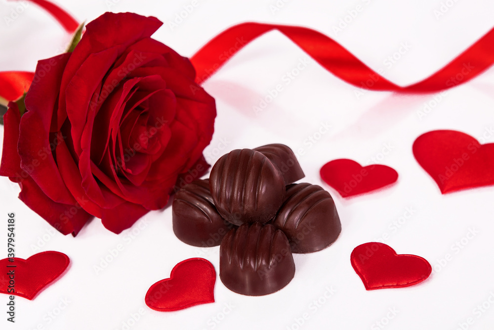 Rose, chocolate hearts and ribbon on a white background