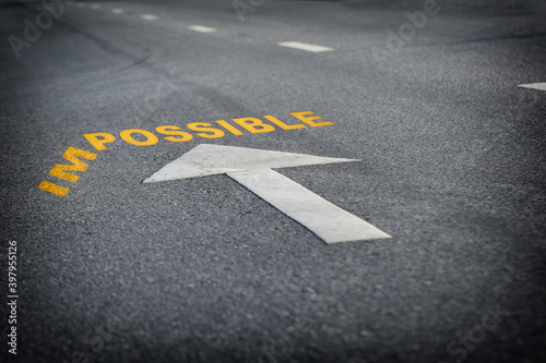 Impossible word without im with arrow on black asphalt road surface, business challenge concept and overcome success idea