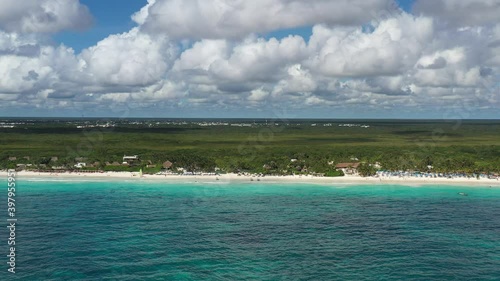 Espectacular vista aérea de Playa Paraiso, en Tulum, México. El drone volando de forma lateral a 150 metros de la costa con un cielo azul y nublado como fondo.
