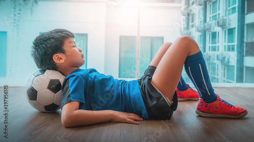 Young Asian Soccer player kid is sleeping on a football under his head. photo