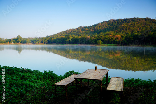    Empty bamboo chairs at By the lake in thailand and The view of the forest changes color on the background. © K.Pornsatid
